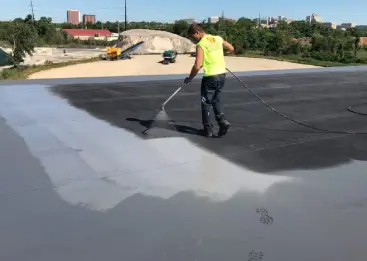 Professional roofer from J. Smucker Contracting applies roof coating